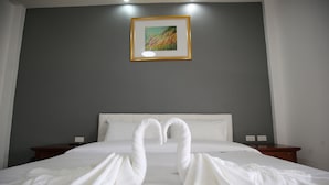 A hotel room with a bed, two nightstands, a painting on the wall, and a swan-shaped towel arrangement.