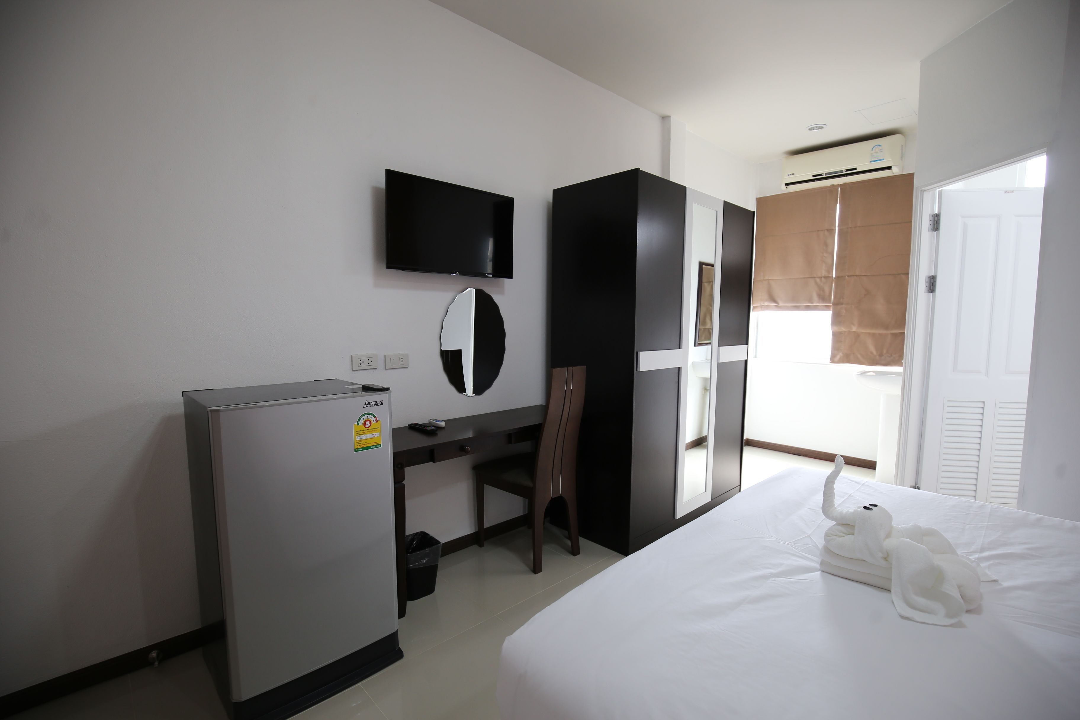 Habitación de hotel con cama, escritorio, silla, televisor y armario.