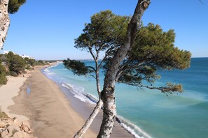 A beach with clear blue waters and a tree in the foreground. - Villa Lyna by Parc Mont-roig (Miami Playa)