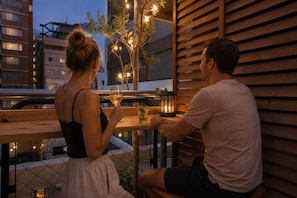 A couple seated at an outdoor table with a view of buildings in the background. - Feel Osaka Yu - Hostel (Osaka)