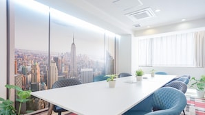 A conference room with a large table, blue chairs, and potted plants. - Feel Osaka Yu - Hostel (Osaka)