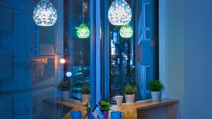 A modern workspace with a long wooden table, multiple laptops, and potted plants. - Feel Osaka Yu - Hostel (Osaka)