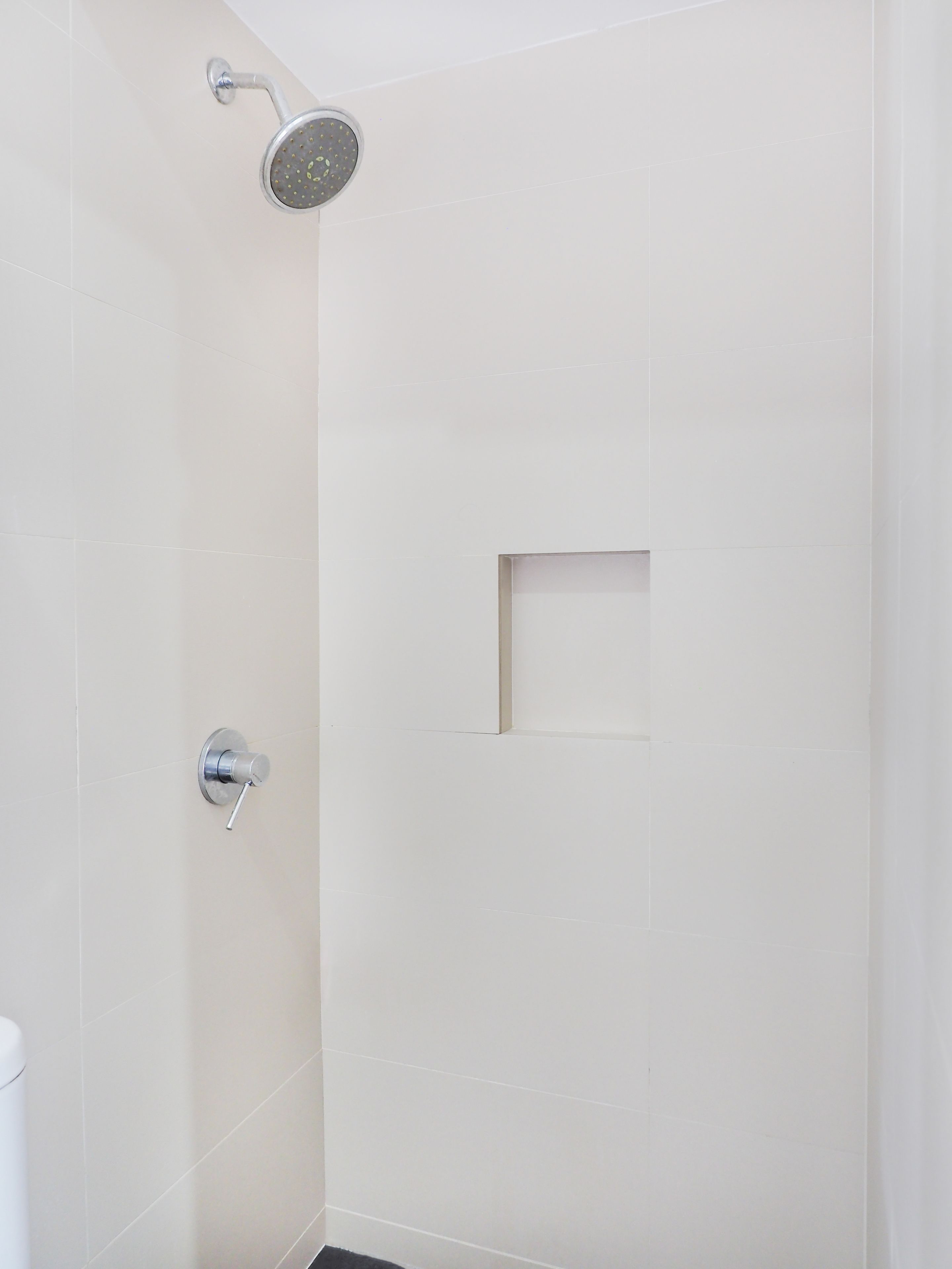 A shower with a handheld showerhead and a wall-mounted control valve.