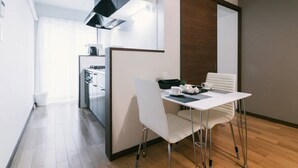 Een moderne keuken met witte kasten, een zwarte afzuigkap, en een eethoek met een witte tafel en stoelen.