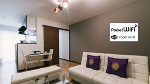 Een moderne woonkamer met een bank, een salontafel en een eethoek met stoelen.