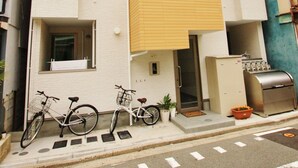 Een meerlaags woongebouw met balkons, een fiets voor de deur en een klein buitenruimte met potplanten.