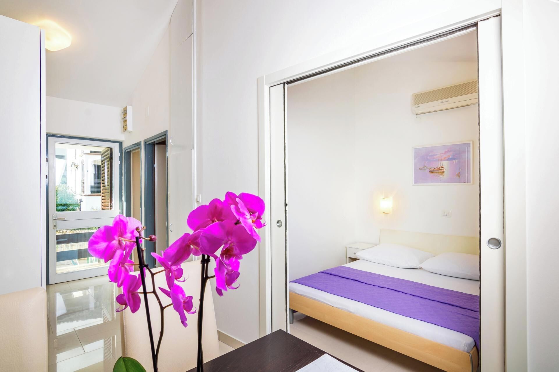 A bedroom with a bed, a nightstand, and a window with a view of the outside.