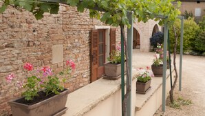A stone building with a rustic charm, featuring a vine-covered pergola and potted plants. - La Forge - Apartment private terrace, overlooking the pool and Roche de Solutré (Vergisson)
