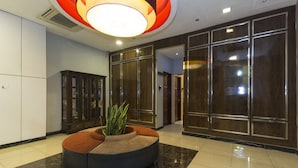 Un hall d’entrée doté d’un espace salon circulaire, d’une grande armoire en bois et d’un luminaire au plafond diffusant une lumière vive.