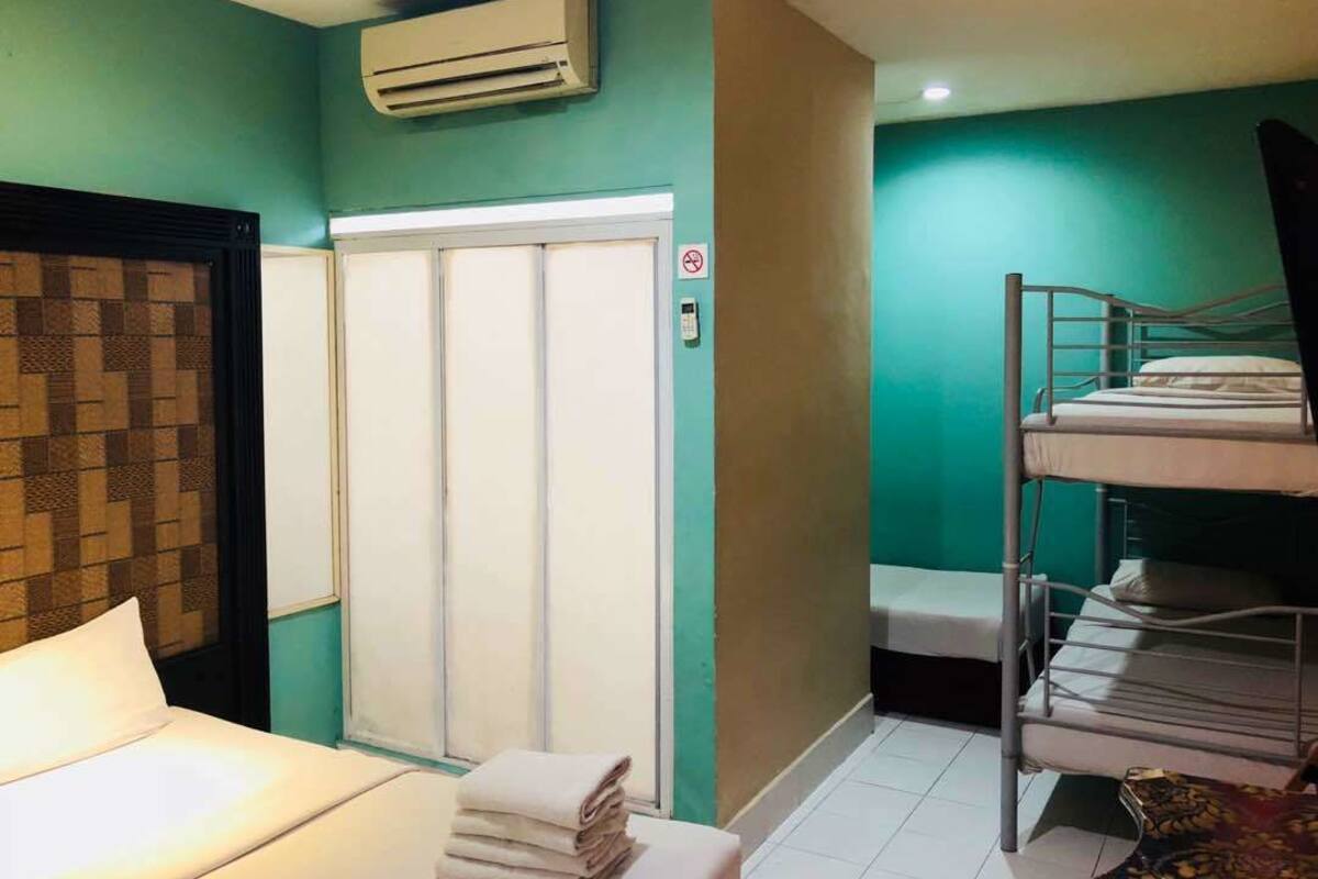 Een hotelkamer met een bed, een stapelbed, een kledingkast en een airconditioning.