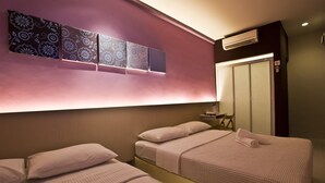 Une chambre d’hôtel avec deux lits, une coiffeuse avec un miroir et un climatiseur fixé au mur.