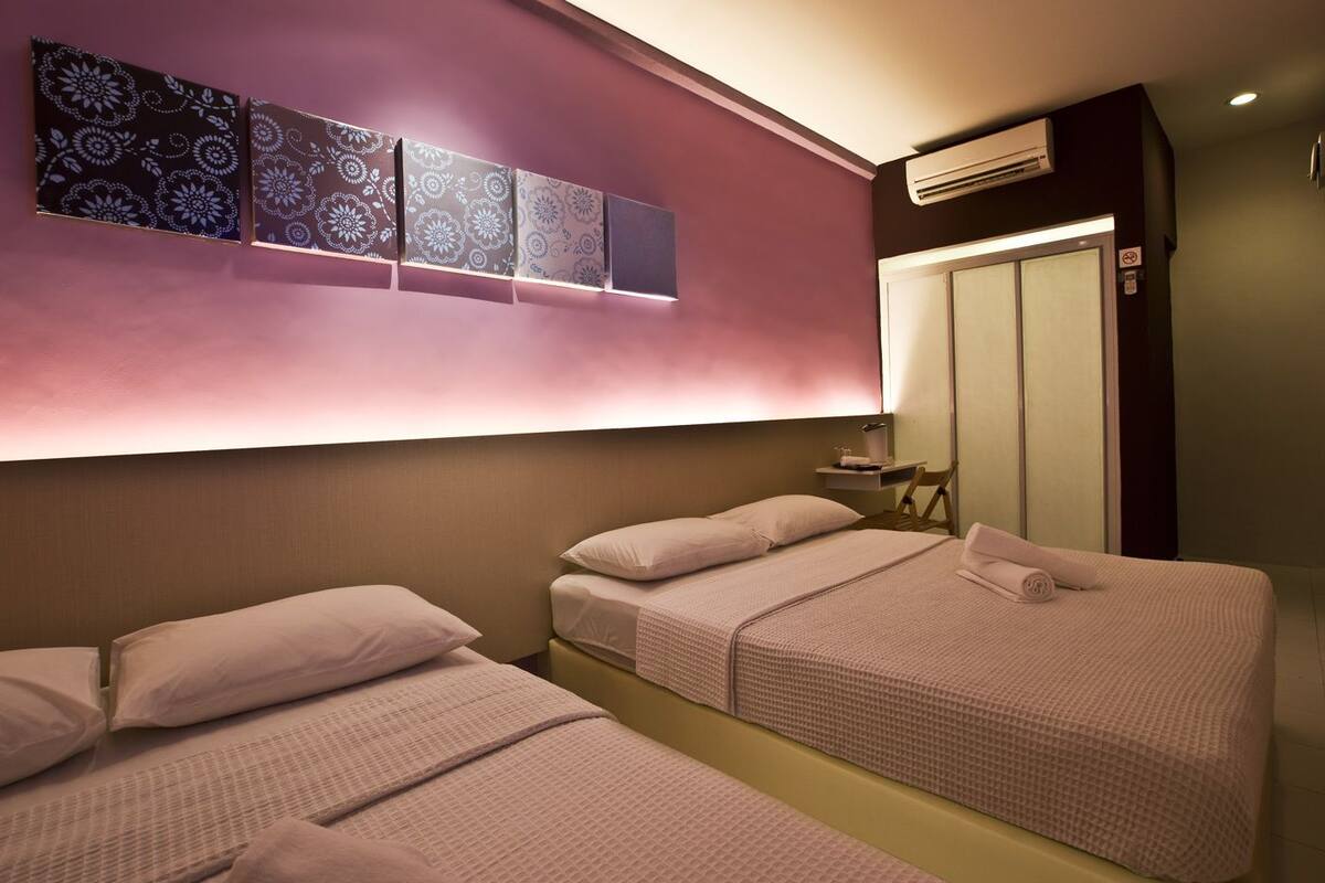 Een hotelkamer met twee bedden, een kaptafel met spiegel en een wandairconditioner.
