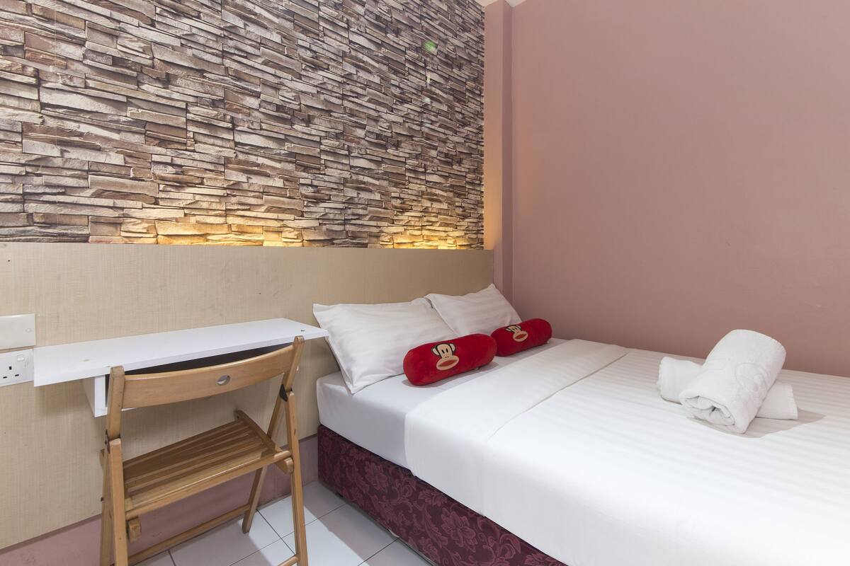 Een slaapkamer met een bed, een bureau en een stoel.