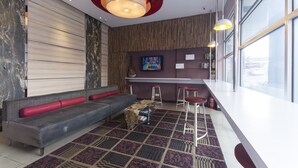 Un espace de vie moderne comprenant un canapé, une table basse et un coin bar avec des tabourets.