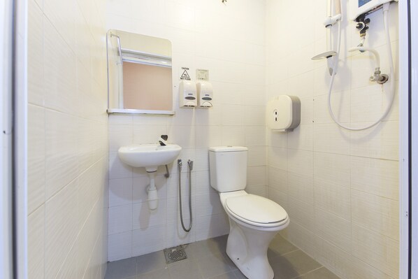 Une salle de bain avec des toilettes, un lavabo et une douche.