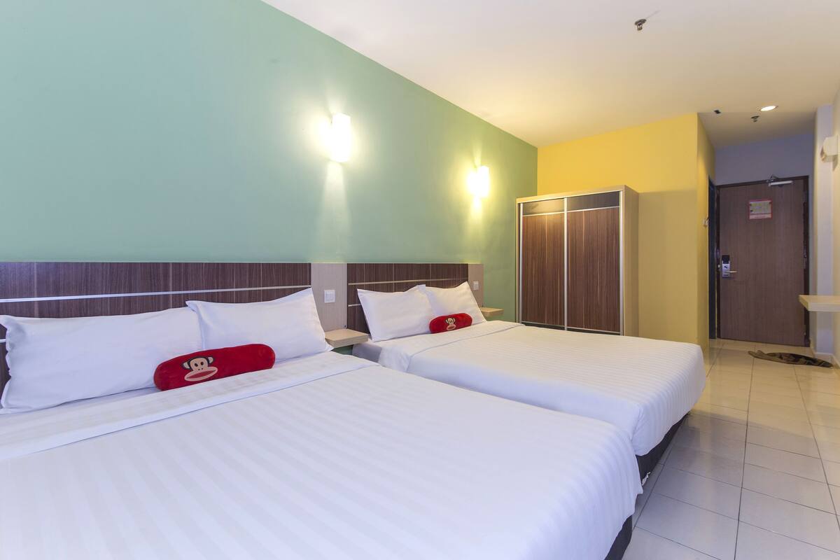 A hotel room with two beds, a wardrobe, and a bathroom.