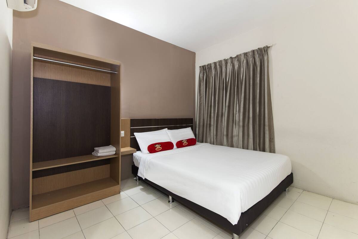 A hotel room with a bed, a wardrobe, and a curtain.