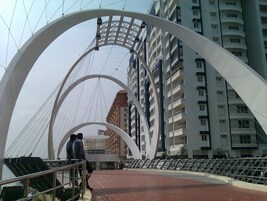 Un puente peatonal de diseño moderno, con amplias arcos blancos y barandilla metálica.