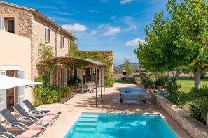 Un espace piscine comprenant des chaises longues, une pergola et une table.