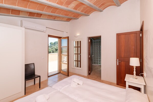 Une chambre à coucher comprenant un lit, une chaise, une porte en bois et une porte-fenêtre coulissante donnant sur un espace extérieur.