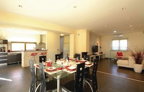 A spacious living area with a dining table set for four, a kitchen with modern appliances, and a comfortable seating area with a sofa and a TV. - Luxury villa with heated pool and large private garden, near the sea (Peroj)
