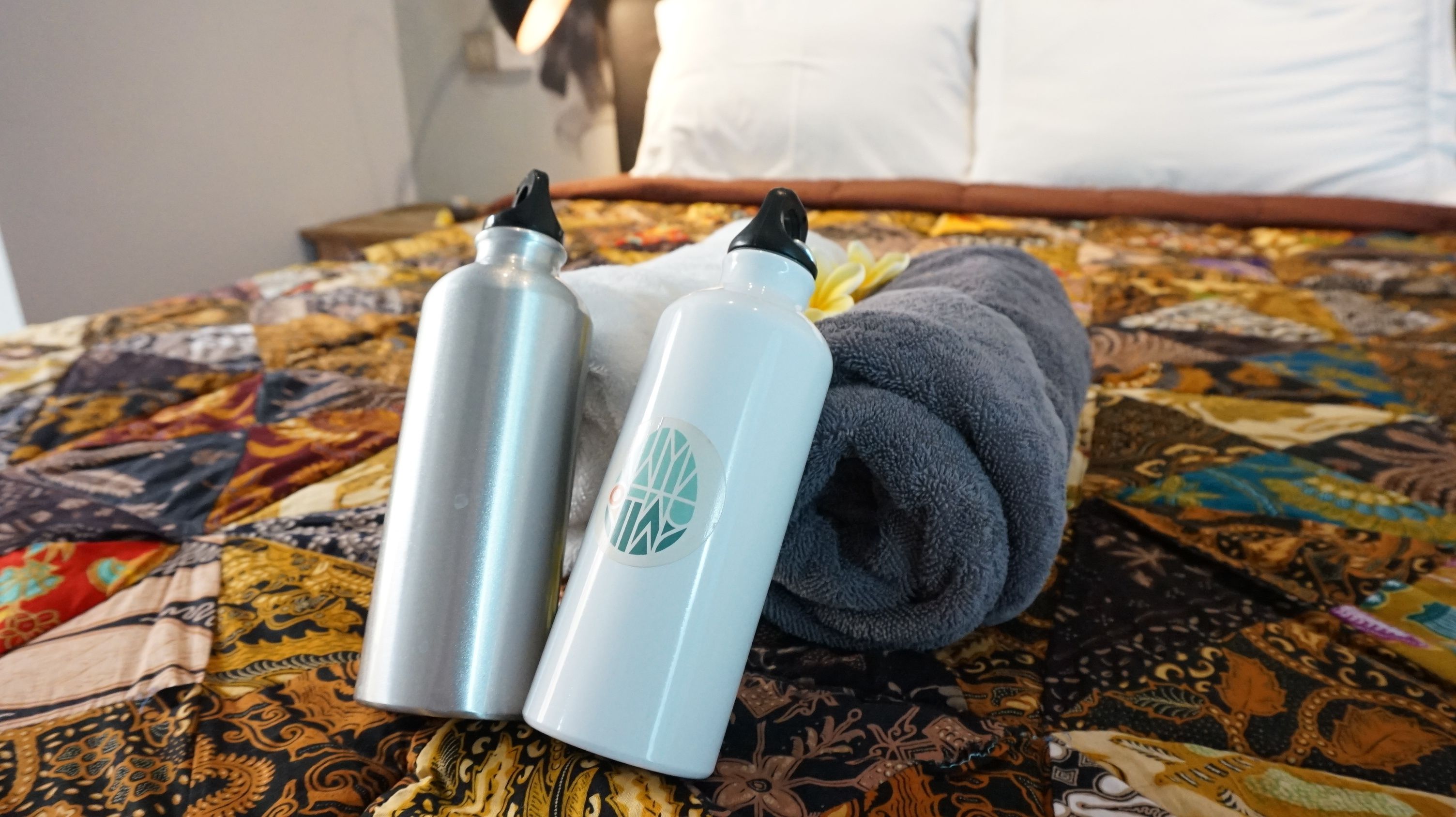 Dos botellas de artículos de tocador sobre una cama con una colcha estampada.