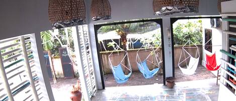 A spacious patio area with hanging chairs, a wooden table, and a view of the surrounding greenery.
