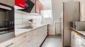 Een keuken met witte kasten, een rode afzuigkap, een magnetron en een koelkast.