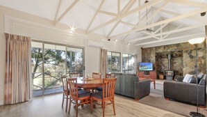 Un amplio salón con una mesa de comedor, sillas, un sofá y una chimenea.