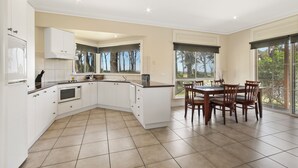 Una cocina moderna con armarios blancos, un microondas y una zona de comedor con sillas de madera.