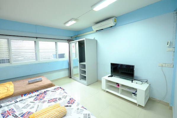 A bedroom with a bed, a TV, a wardrobe, and a window. - Orion Apartment (Bangkok)