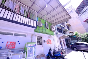 A building with a green and white facade, a balcony with a metal railing, and a parked motorcycle. - Orion Apartment (Bangkok)