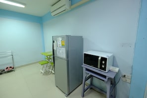 A room with a refrigerator, microwave, and a small table with a chair. - Orion Apartment (Bangkok)