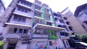 A multi-story building with balconies, air conditioning units, and a sign indicating a business on the ground floor. - Orion Apartment (Bangkok)