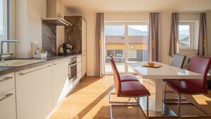 A modern kitchen with white cabinets, a stainless steel range hood, and a large window overlooking a mountainous landscape. - Panorama App 2A am See, für max.4,free WIFI (Zell am See)