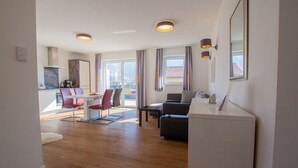 A modern living room with a dining area, a sofa, a coffee table, and a flat-screen TV. - Panorama App 2A am See, für max.4,free WIFI (Zell am See)