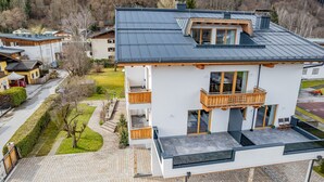 A modern two-story building with a balcony, a stone pathway leading to the entrance, and a view of the surrounding neighborhood. - Panorama App 2A am See, für max.4,free WIFI (Zell am See)