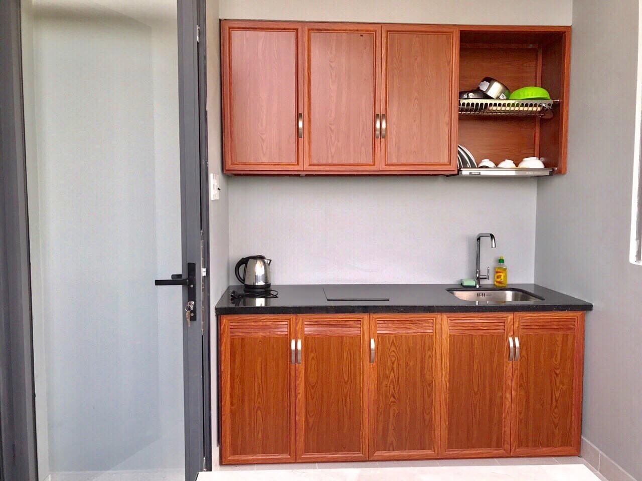A compact kitchen with wooden cabinets, a black countertop, and a stainless steel sink.