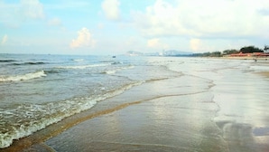 Een strand met golven, een verre stadshemel en een heldere lucht.
