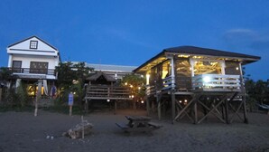 Una propiedad frente al mar, con un edificio principal y una estructura de madera con balcón.
