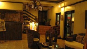 Un hall acogedor con muebles de mimbre, una escalera y un candelabro.