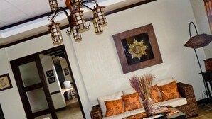 Un salón con muebles de mimbre, una araña y una decoración con diseño de sol en la pared.