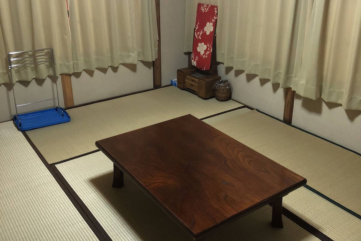 A tatami mat room with a wooden table, a blue mat, and a traditional Japanese screen.