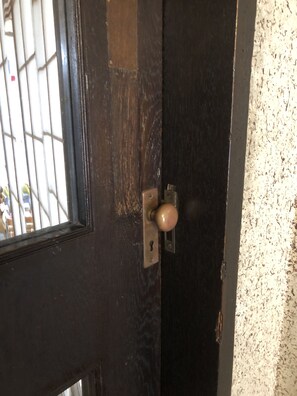 A door with a keyhole and a round knob, partially open.