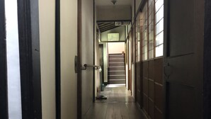 A narrow hallway with wooden flooring, a door on the left, and a window on the right.