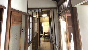 A narrow hallway with wooden beams on the ceiling and traditional Japanese sliding doors on either side.