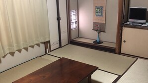 A tatami mat room with a wooden table, a TV, and a small cabinet.