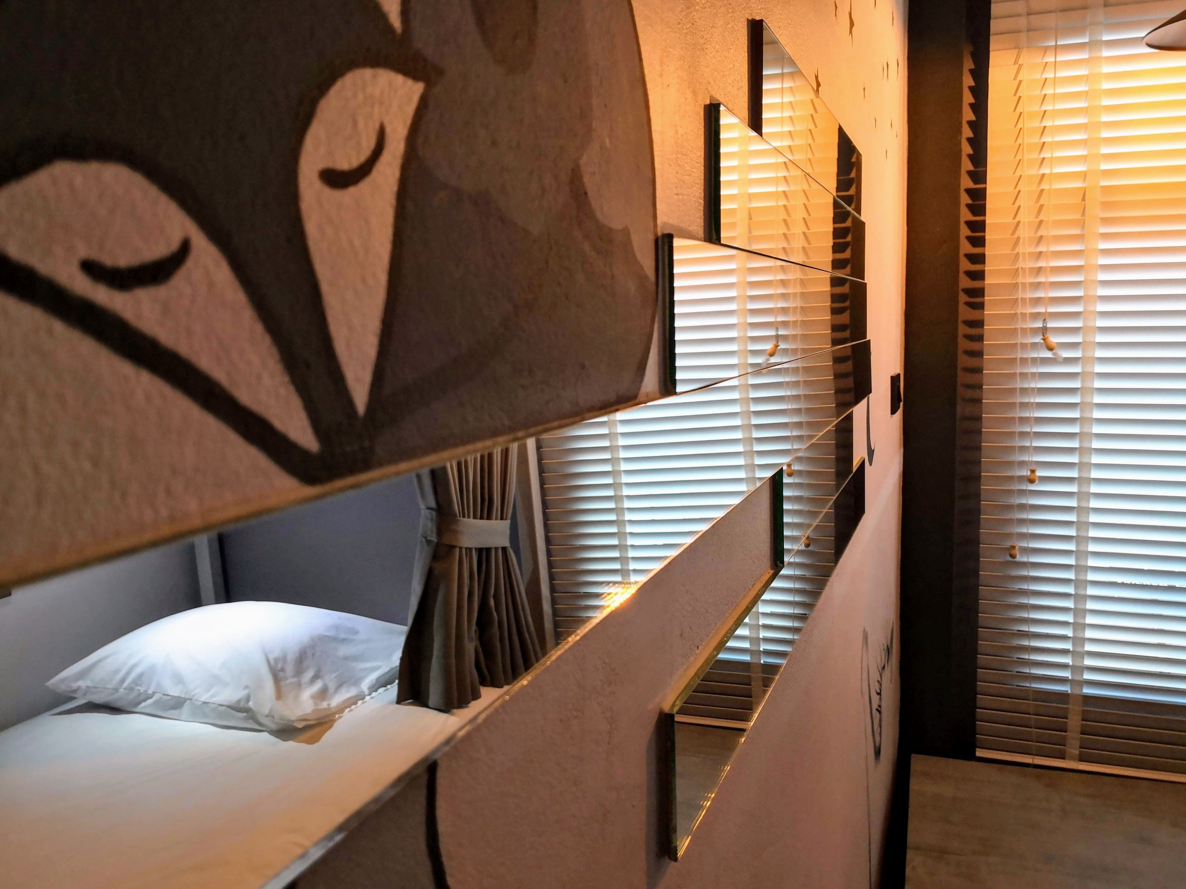 A hotel room with bunk beds, a curtain, and a window with blinds.