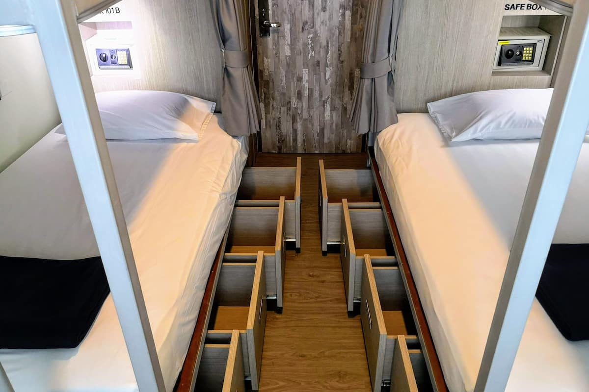 Une chambre avec des lits superposés, un coffre-fort et un rideau.