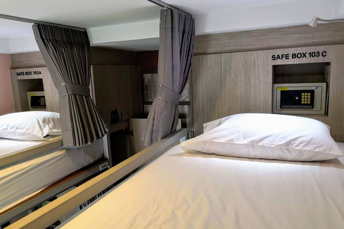 Une chambre d’hôtel avec deux lits, un coffre-fort portant l’étiquette « COFFRE-FORT 103 C », et un panneau de commande pour le coffre-fort.